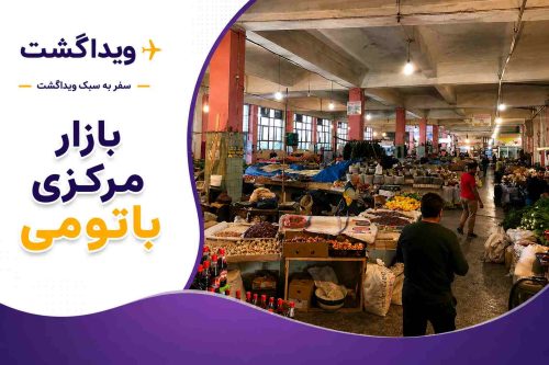 نمای داخلی بازار مرکزی باتومی با غرفههای فروش میوه، سبزیجات، خشکبار و محصولات محلی گرجستان به همراه لوگوی ویداگشت.