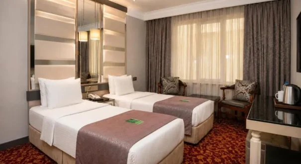 اتاق تویین هتل ریفرم وان با دو تخت یک‌نفره و فضای نشیمن